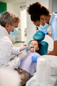Dentista atendiendo a un niño junto a una asistente en la Clínica Elena Queral en Castellón.