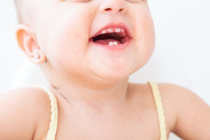 Bebé sonriendo con sus primeros dientes de leche visibles